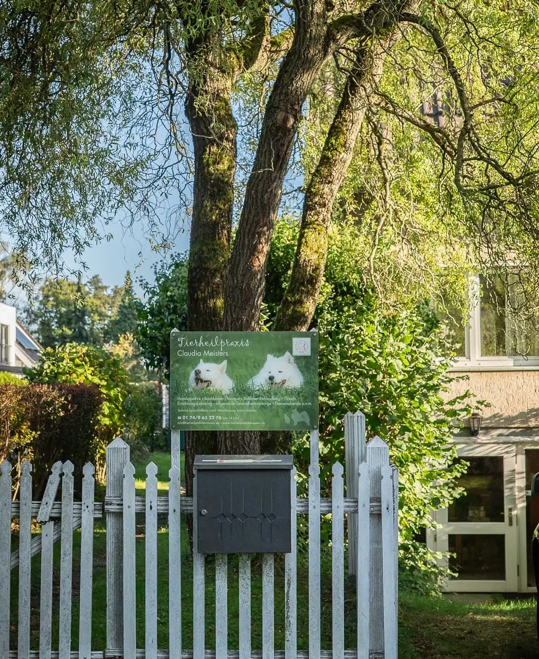 Eingang der Tierheilpraxis Claudia Meisters in Mülheim an der Ruhr mit Praxisschild und Gartenzaun